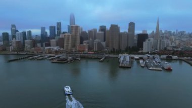 Alacakaranlıkta çekilen güzel San Francisco siluetinin nefes kesen görüntüsü şehrin hareketli limanlarını ve hafif sis ve feribotla çevrelenmiş parıldayan şehir ışıklarını vurguluyor.