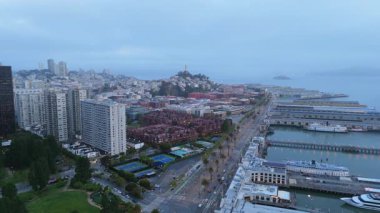 Hava görüntüleri San Francisco 'yu alacakaranlıkta yakalıyor, körfezi, işlek limanı ve ikonik silueti sergiliyor, akşam sisi ile örtülmüş, büyüleyici, büyülü bir dokunuş ekliyor.