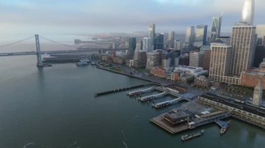 San Francisco 'nun nefes kesici ufuk çizgisini, körfeziyle birlikte gösteren binaları, ikonik köprüleri ve alacakaranlıkta hareketli limanı gösteren nefes kesici hava görüntüsü.