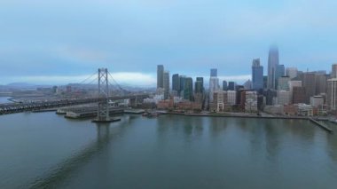 Arka planda Embarcadero ve Financial District gökdelen binaları olan Bay Bridge 'in hava manzarası. San Francisco şehir merkezi, karanlık yaz gece lambası. 4K B-roll insansız hava aracı aydınlatılmış gece şehri sahnesi