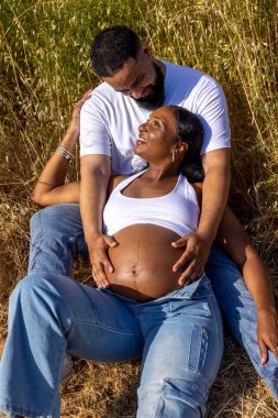 Sevecen bir Afrikalı Amerikalı çift, doğadaki hamileliklerini kutlamak için dışarıda bir yaz gününün tadını çıkarıyor. Koca, karısına sarılıyor ve ebeveynliğe olan yolculuklarının tadını çıkarıyor.