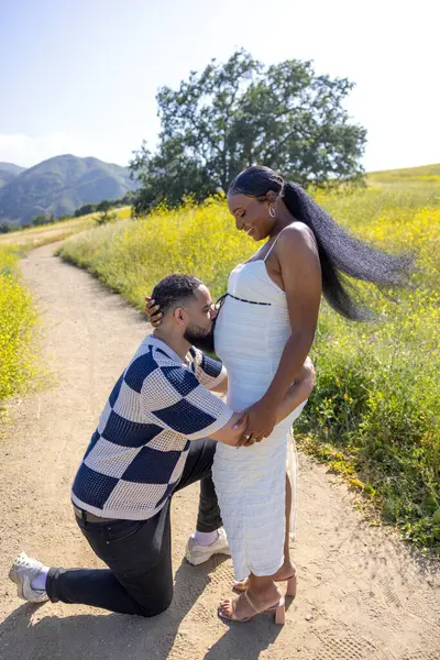 Sevgi dolu bir çift dışarıda unutulmaz bir anı neşeyle paylaşıyor. Doğaları gereği nefes kesici güzellikleri ve güneşin sıcaklığıyla çevrelenmiş, sabırsızlıkla bekledikleri aile genişlemesini kutluyorlar.