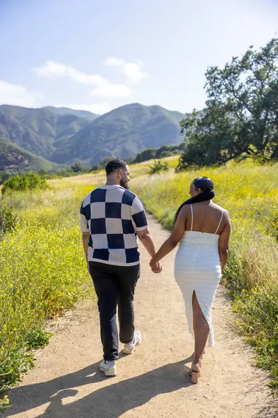 Sevgi dolu bir Afrikalı Amerikalı çift, mutlu bir şekilde el ele yürür. Resimli bir yaz manzarasında, hamileliğin mutluluğunu ve etraflarındaki doğayla olan derin bağlarını kutlar.