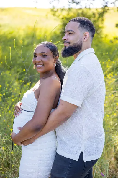 Gerçekten iç açıcı bir anda, güzel bir kucaklaşmayı paylaşan neşeli bir çifte tanık oluyoruz. Kocasının hamile karısını sevgiyle kucakladığına doğayla çevrili sakin bir ortamda.