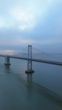 Yumuşak sisin körfezi kapladığı San Franciscos ufuk çizgisinin çarpıcı hava manzarasını deneyin. Bu pitoresk kentsel manzaranın cazibesini ve canlı liman aktivitelerini artırın.