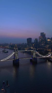 Gece aydınlık Tower Köprüsü 'nü gösteren bir hava manzarası Londra ufuk çizgisini ve Thames Nehri' ni alacakaranlık zeminine karşı sergiliyor ve ziyaretçiler ve fotoğrafçılar için büyüleyici bir sahne yaratıyor.