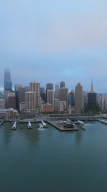 Hava fotoğrafı San Francisco 'nun göz kamaştırıcı ufuk çizgisini yakalar, körfezi ve işlek limanı gösterir, simgesel binaları hafif sis kaplar, sakin, sinematik bir atmosfer yaratır.