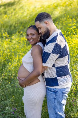 Bir yaz günü, sevecen bir Afro-Amerikan çifti, çevresi yeşilliklerle çevrili olan, hamileliklerini sevinçle kutlayan ve yolculuklarını sıcak bir şekilde kucaklayan bu anın tadını çıkarır.