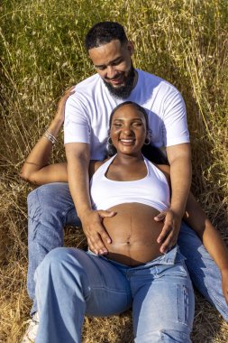 Afrika kökenli Amerikalı bir çift yaz mevsimini neşeyle kucaklıyor. Koca, karılarını nazikçe okşuyor. Açık havada bebek çarpması, geleceğe olan sevgilerini ve heyecanlarını yansıtıyor.