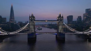 Bu hava manzarasında Tower Bridges çarpıcı bir mimari sergiliyor, Londra siluetine karşı aydınlatılmış, Thames Nehri 'nin üzerinde yansımalar parıldıyor, büyüleyici bir sahne yaratıyor.