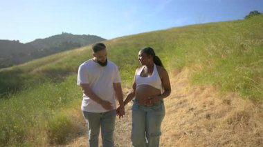 Neşeli ve beklenen Afro-Amerikan çifti, doğaya dalmış güzel bir yaz gününün keyfini çıkarırken, önlerinde uzanan heyecan verici ebeveynlik yolculuğunu kucaklarken, bağlantılarını derinleştiriyorlar.