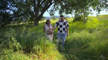 Güneşli bir günde, neşeli bir Afrikalı Amerikalı çift ilk çocuklarının yemyeşil alanda el ele yürümesini bekliyor. Aşklarını ve yeni hayatın heyecanını kutluyorlar.