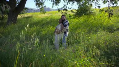 Güzel bir yaz manzarasında, sevecen hamile Afrikalı Amerikalı çift, çevrenin yeşilliklerle çevrili olduğu hassas bir anı paylaşıyor. Ailelerine katılacakları için sevinçle kutluyorlar.