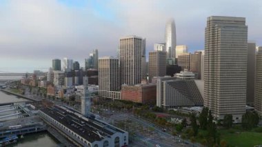 Hava aracı görüntülerinde şafak vakti San Franciscos silueti, körfez, işlek liman ve bu ünlü iş merkezinin güzelliğini ve ikonik simgelerini artıran hafif sis görülüyor.