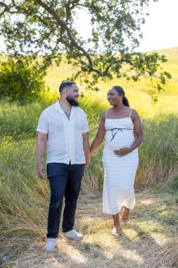 Sıcak bir yaz gününde, neşeli hamile bir çift doğanın tadını çıkarır. Sevgisine ve doğacak bebeğine değer verir. Yumuşak güneş ışığına boğulur, yeşilliğin içinden süzülür.