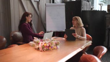Şık bir ofiste, iki başarılı iş kadını, aktif işbirliğinin ve modern çalışma kültüründe etkin takım çalışmasının önemini vurgulayan anlamlı bir tartışmaya girişirler.