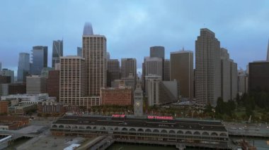 San Francisco üzerinde çekilen nefes kesici hava görüntüleri ikonik ufuk çizgisini ve akşam sisi içindeki hareketli limanı gözler önüne sererken, canlı şehir ışıkları aşağıda parıldıyor.