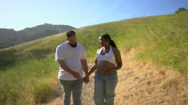 Bebek bekleyen mutlu bir çift, doğanın güzelliğini neşeyle kucaklıyor. Dışarıda dinlenirken, sıcak yaz güneşinin tadını çıkarırken sevgi ve huzur dolu anları paylaşıyorlar.