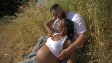 Sevgi dolu bir çiftin, huzurlu ve resimli bir doğal ortamda güzel bir hamilelik fotoshoot sahnesinde şefkatle kucakladığı büyüleyici ve iç açıcı anlar.