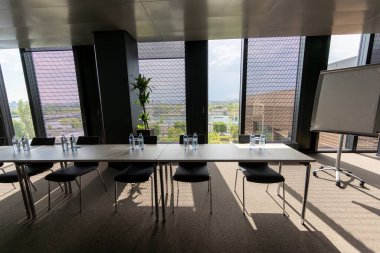 Bu modern konferans odasında, verimli toplantılar ve ilham verici sunumlar için ideal bir ortam oluşturan geniş bir masa, rahat sandalyeler ve manzaralı büyük pencereler yer alıyor.