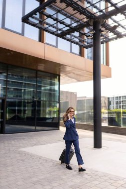 Şık bir donanma kıyafeti giymiş kendine güvenen bir profesyonel modern bir ofis binasının yanında enerjik bir şekilde iş günlerini meşgul ederken telefonla konuşuyor.