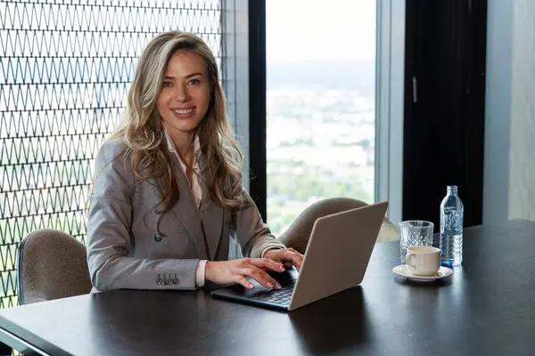 Özel dikim takım elbiseli kendine güvenen bir iş kadını yoğun bir şekilde bilgisayarına odaklanarak modern ofis ortamındaki özveri, konsantrasyon, yetenek ve profesyonel uzmanlığını gösteriyor.