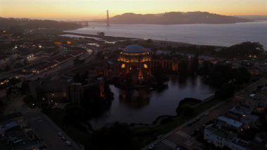 Güzel Sanatlar Sarayı ve Golden Gate Köprüsü 'nün nefes kesici günbatımı manzarası, California mimarisi ve kültürünün gezginler ve fotoğrafçılar için hayat dolu sahnesini vurguluyor.
