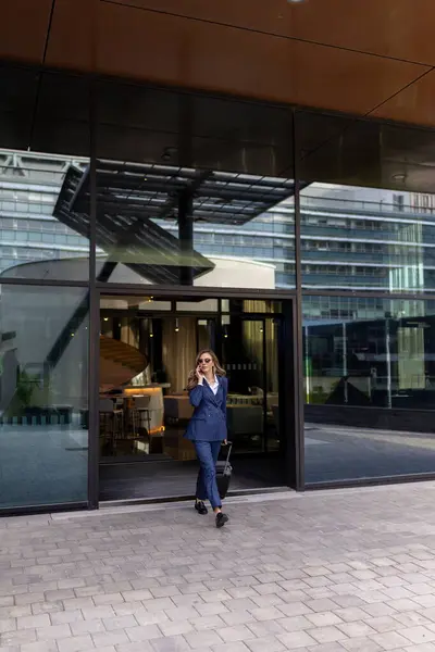 İyi giyimli bir profesyonel, çarpıcı derecede modern bir ofis binasından çıkıyor. Etkileyici mimari tasarımını ön plana çıkarırken onları çevreleyen canlı kentsel yaşam tarzını benimsiyor.