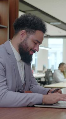 Modern bir ofiste, kendini işine adamış bir işadamı laptopun etrafında bir meslektaşıyla işbirliği yaparak, etkin takım çalışmalarını ve dinamik bir çalışma alanında proje hedeflerine ulaşma kararlılığını sergiliyor.