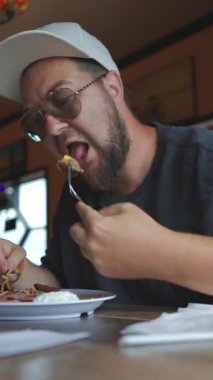 Bir adam küçük, rahat bir restoranda nefis bir yemek yiyor. Ağzını sulandıran yemekler ve onu rahatlatan iyi hislerle dolu gündelik yemek anlarını sergiliyor.