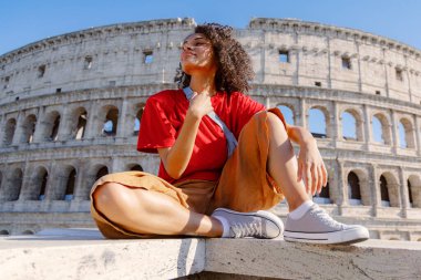 Neşeli bir gezgin, sembolik Colosseum 'un önünde gururla durur ve antik tarihin, çarpıcı mimarinin ve modern tarzın enfes bir karışımını güzel bir şekilde gösteren bir anı yakalar.