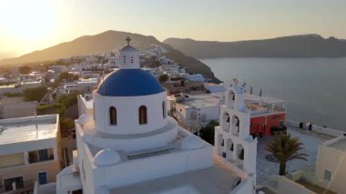 Santoriniler nefes kesici güzellikte ikonik mavi kubbelerin deniz manzarası ve yemyeşil tepeler, özellikle manzarayı güzelleştiren pitoresk günbatımları sırasında