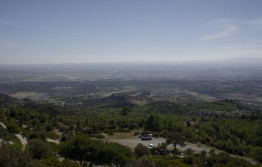 Kıbrıs 'taki dağların tepesinden vadinin manzarası. Önplanda dağların yamacında bir orman..