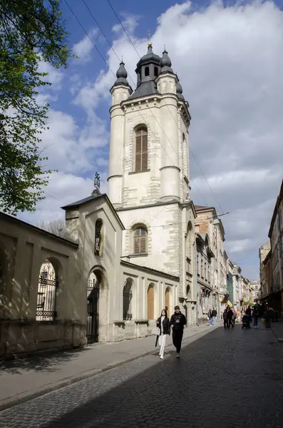 Ukrayna Lviv 28 Nisan 2023, güneşli bir günde yaşlı Lviv caddesinde katedral çan kulesiyle.