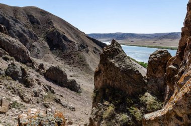 Dağ Nehri, Arid Kanyon Vadisi boyunca Rocky yamaçları ve berrak mavi sularıyla akıyor..