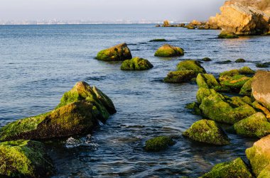 İçlerinde açık denizle akan kayaların olduğu deniz kıyısı..