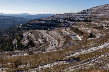 snowy mountain scenery crossed by a road with several vehicles on it