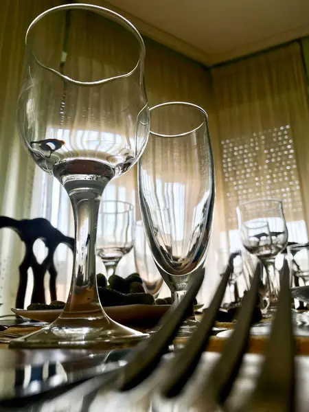 Üzerinde birkaç bardak ve çatal olan bir masa. Bardakların çoğu boş ve çatallar düzgünce dizilmiş. Sahne sakin ve huzurlu, sanki birisi sessiz bir yemeğin tadını çıkarmak üzereymiş gibi.