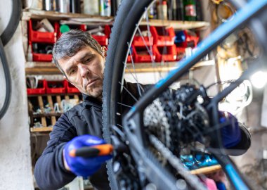 Cycling technician repairing and maintaining bike and chain mechanism in workshop