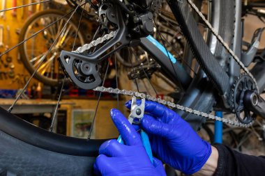Cycling technician repairing and maintaining bike chain in workshop