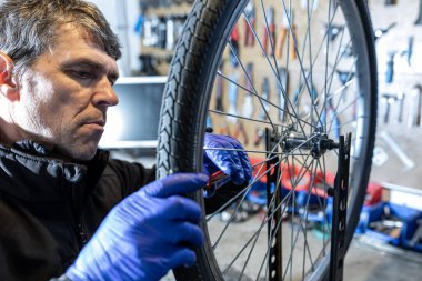 Cycling technician repairing bike wheel and spokes in workshop