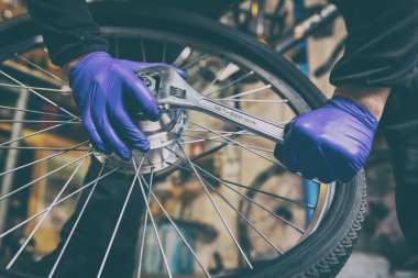 Cycling technician repairing and maintaining bike and wheel in workshop