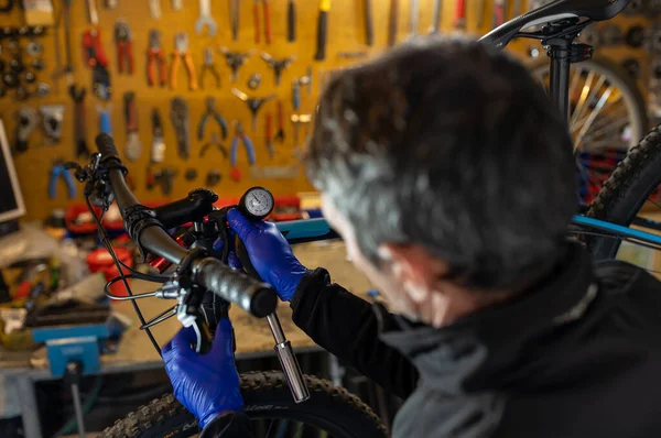 Cycling technician repairing and maintaining bike and shock absorbers in workshop