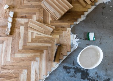 Top view of parquet boards installing in herringbone arrangement with tools, home flooring concept