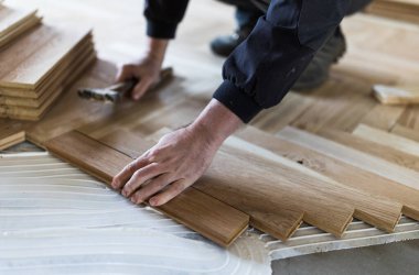 Experienced worker installing parquet boards in glue in new house