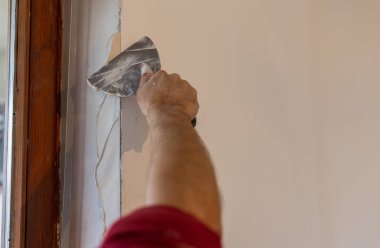 Close up of male hand putting plaster on wall in home renovation process