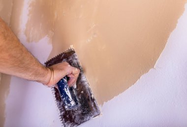 Close up of male hand putting plaster on wall in home renovation process