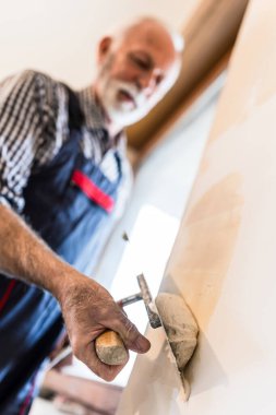 Close up of old man hand working with plaster on walls