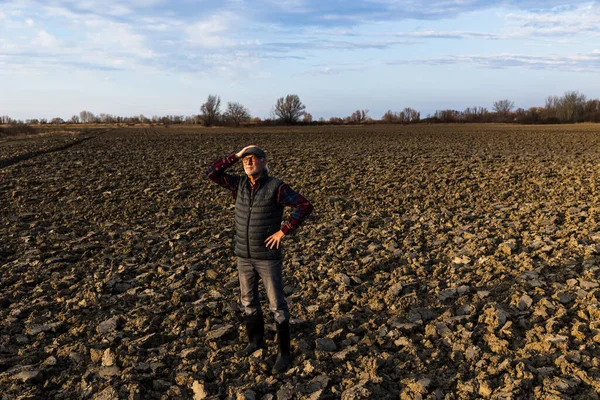Ανώτερος Αγρότης Στέκεται Οργωμένο Χωράφι Χειμωνιάτικη Ηλιόλουστη Μέρα — Φωτογραφία Αρχείου