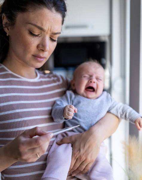 Mãe Preocupada Segurando Bebê Chorando Uma Mão Casa Olhando Para — Fotografia de Stock